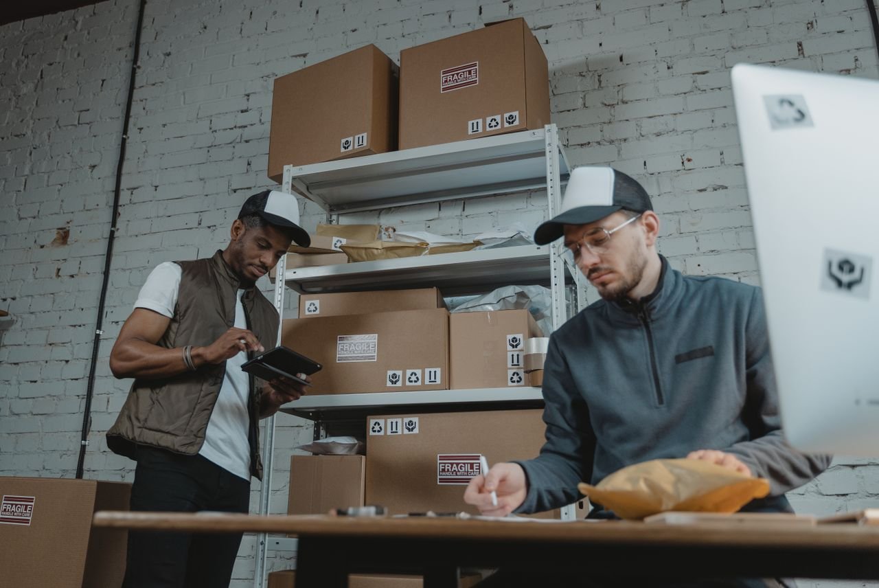 Home Two warehouse employees organizing and packing parcels for delivery in a modern indoor setting.